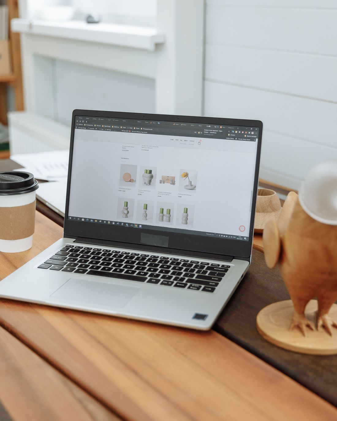 A laptop on a wooden desk showing a website design, with coffee alongside