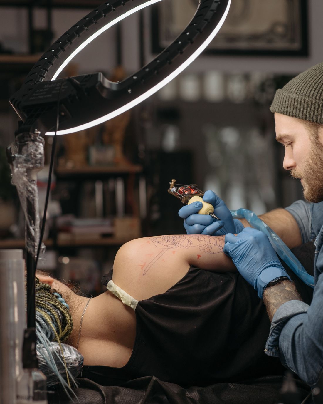 A tattoo artist working on a client's forearm