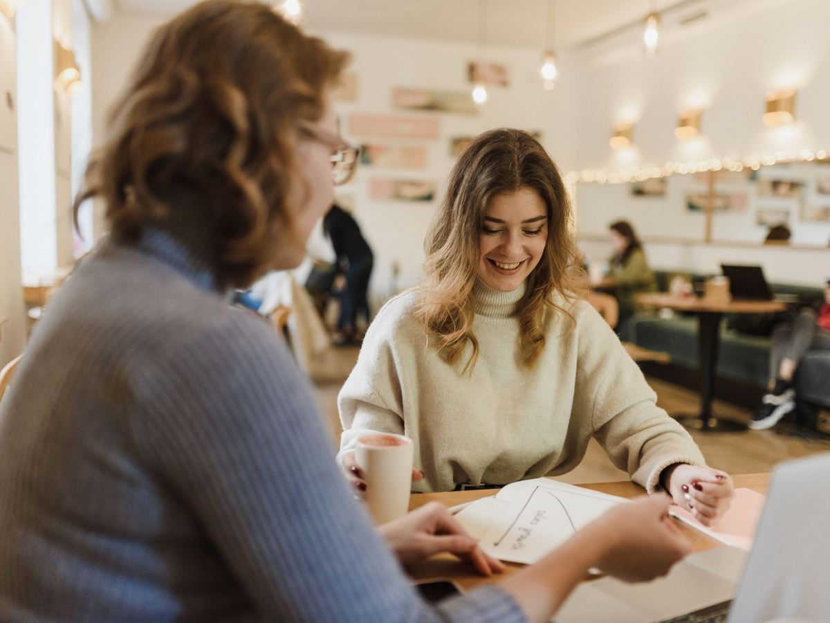 Two colleagues talking over paperwork at an informal cafe table