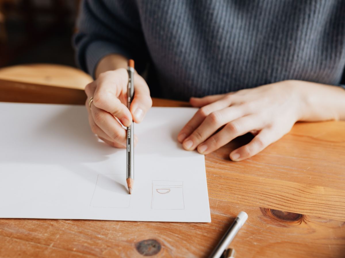 A hand sketching a rough plan on paper