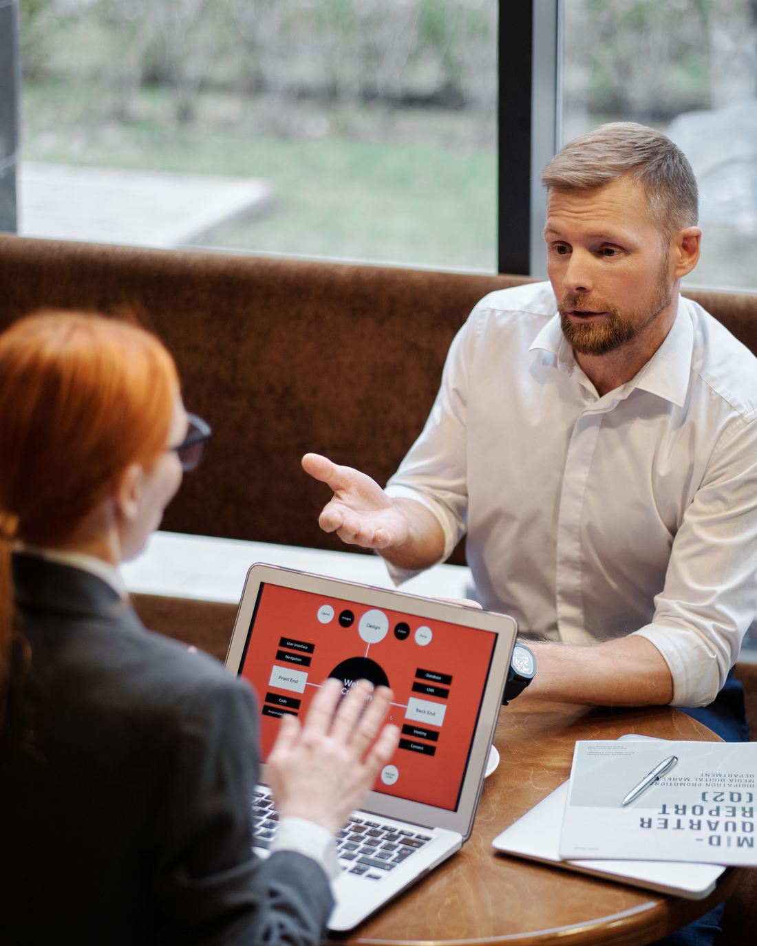 A website structure open on a laptop while two people talk it through